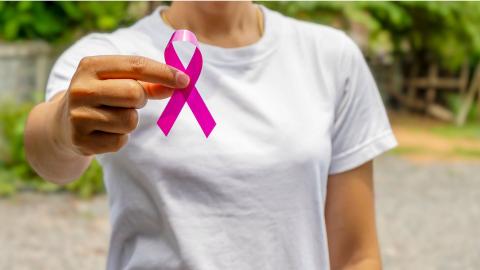 Femme qui montre un ruban rose dans le cadre de l'opération Octobre rose pour la prévention du cancer du sein