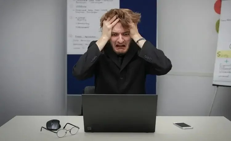 Un homme devant un ordinateur s'arrachant les cheveux pour ses démarches administratives