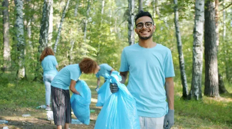 Jeunes bénévoles ramassant des déchets en forêt, portant des sacs poubelle