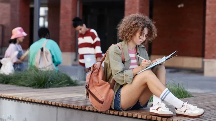 jeune étudiante travaillant assise dehors